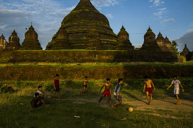 Boys play football in front of an ancient temple from the era of the Kingdom of Arakan.