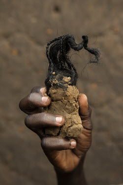 A clay doll figure, with hair made from a woman's braided extentions, made by Simon Ayole (13), a refugee boy living in the Bidibidi camp.  According to the UNHCR 60% of the refugees fleeing South Sud...