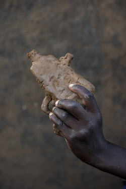Falidi Aharo (8), a boy living in a village intergrated with the Bidibidi Refugee Settlement, holds a homemade clay toy gun.