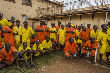 Fans, wearing yellow and orange uniforms, depending on their status in the jail, watch a football match played at Luzira Prison between teams composed of inmates, Liverpool FC versus Manchester United...