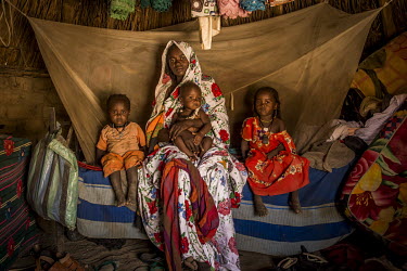 Houra Hassan (27), and her three daughters, sit together in the family hut on the only bed. In her arms, she holds Mariam (9 months), on the left is Adijo (3.5) and to the right is Adija (5).   Many m...