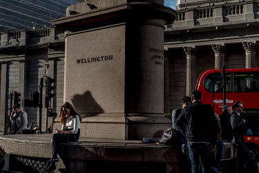 People take a break at the base of the Wellington statue in front of the Royal Exchange in London.