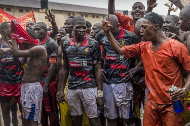 Supporters congratulate players following a football match played at Luzira Prison between teams composed of inmates, Liverpool in black versus Manchester United in Red. A league, made up of several s...