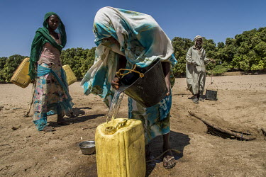 Adjoua Abakar (19), the mother of two girls, fills a jerrycan with water collected from a well in the middle of a dry river bed next to her home in Mourra village. Her husband left two years before to...