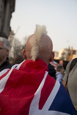 A man with a mohican hair cut and wrapped in a Union Jack joins Brexit supporting protesters, aggrieved that Britain hasn't left the European Union yet, gathered for a rally in Parliament Square.