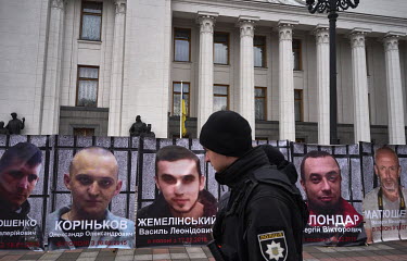 A policeman passes portraits outside the Verkhovna Rada of Ukrainian (national parliament) military intelligence officers captured in East Ukraine.