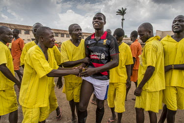 Supporters congratulate a player following a football match played at Luzira Prison between teams composed of inmates, Liverpool in black versus Manchester United in Red. A league, made up of several...