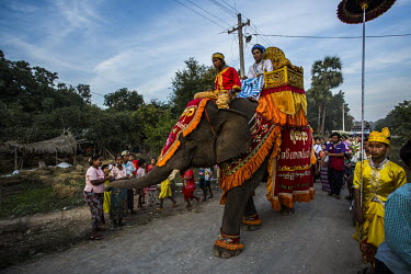 Pho Khwar, an 18 year old elephant, and his mahout Kalu Say, also 18, traditionally dressed for a ceremony they've beem hired to perform in by a family whose children are being ordained as novice monk...