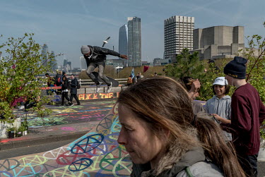 A youth rides a skateboard near people taking part in an Extinction Rebellion protest at Waterloo Bridge.