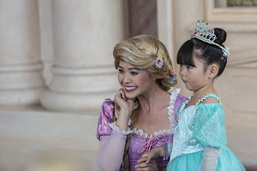 An actress dressed as Rapunzel poses for pictures with a young girl at Walt Disney's Shanghai Disneyland theme park during a trial run ahead of its official opening.