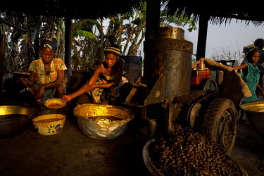 A family work by lamp light to process palm oil. The lack of electricity limits the family's ability to work and therefore reduces their earnings caperbility.