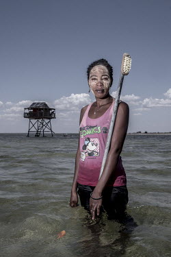 Odette Vinike (27) in the sea-cucumber fields with a brush she uses to keep the pens clean. 'The work is much easier than fishing and catching octopus. We don't need to feed them as they just eat from...