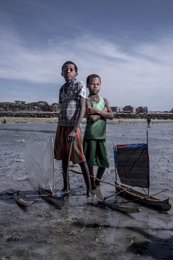Friends Ramavu (11) and Jean Claude (7) on the beach with their homemade toy boats near their home in the Bay of Assassins. Life in the bay revolves entirely around the sea, and children are brought u...