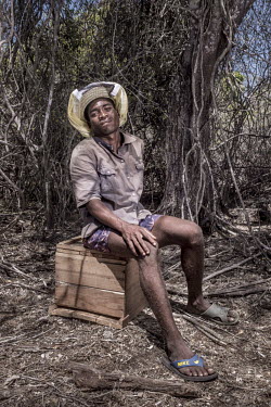 Germain Tsikoro (38) sits by his beehive in the forest near Ankinajoke village. Beekeeping is an alternative source of income helps to reduce the burden on marine species. [This photo story was shot a...