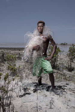 Ripy (20) a shrimp fisherman, with his nets in the Bay of Assassins. Ripy fishes around the margins of the mangroves, which provide a safe nursery for a wide array of species. [This photo story was sh...