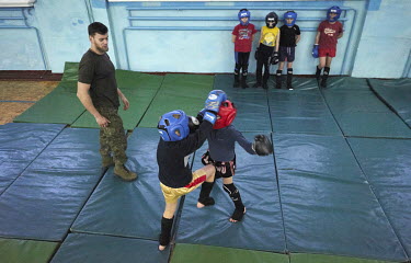 Oleksiy Yukov watches children fighting during a Thai boxing lesson. Oleksiy Yukov is from the Black Tulip humanitarian organisation, which searches for the bodies of missing people, has trained peopl...