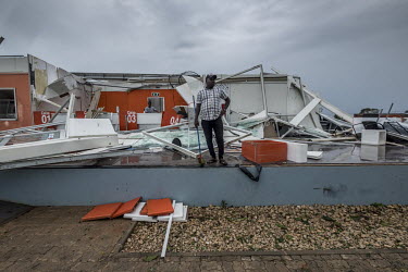 An employee of a bank stands among the wreckage of the building with a broom in his hand as he surveys the destruction left behind by cyclone Kenneth.