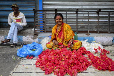 A woman selling flower garlands from a street stall.