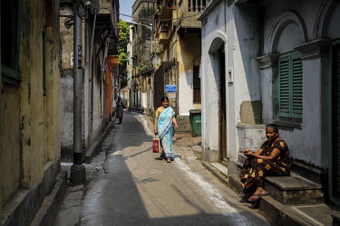 Women on a residential street, lined with colonial-era buildings.