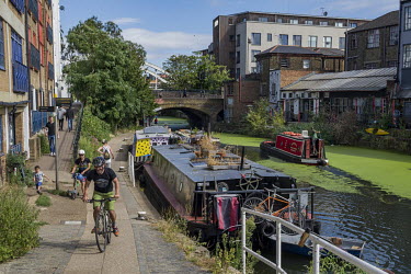 Cyclists and pedestrians pass a narrow boat moored on the Regent's Canal in Haggerston.