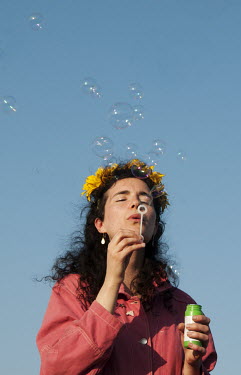 Hannah from Bow, in East London with sunflowers in her hair blows bubbles at Waterloo Bridge during the Extinction Rebellion protests.