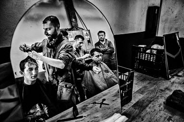 Syrian refugees, who have opened a barber's shop in the Bira International Organization for Migration (IOM) refugee camp, cutting their customer's hair.