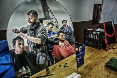 Syrian refugees, who have opened a barber's shop in the Bira International Organization for Migration (IOM) refugee camp, cutting their customer's hair.