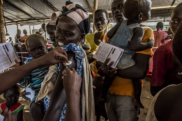 A South Sudanese refugee woman grimaces as she receives a vaccination from a medic at the Imvepi reception centre.