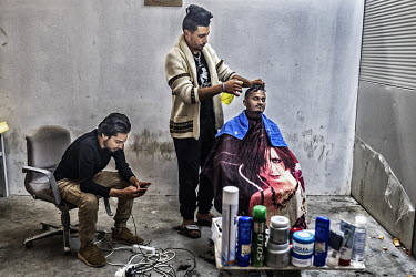 An Afghan refugee, who have opened a barber's shop in the International Organization for Migration (IOM) refugee camp, cuts a customer's hair.
