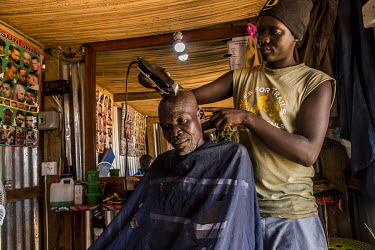In the Good Bless Salon, Morris Ludana, a young South Sudanese refugee hairdresser, crops the hair of a client. This is the first saloon installed in Bidbidi zone #2. A standard haircut cost 1.000 Ug...