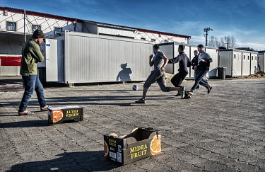 Refugees play a game of football, using old fruit boxes for goalposts, in the courtyard of an International Organization for Migration (IOM) refugee camp.