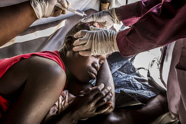 A young South Sudanese refugee woman who was hurt when she tried to break up a fight between two people has a cut treated in the outpatient's clinic at the MSF health centre in Bidibidi.
