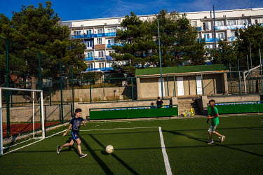 Children play soccer on an artificial pitch.