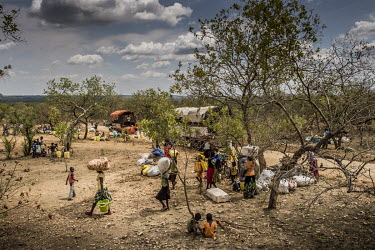 In the Bidibidi settlement area, South Sudanese refugee families with their belongings are dropped by trucks beside a road near the area where plots allocated to their families are located. A family s...