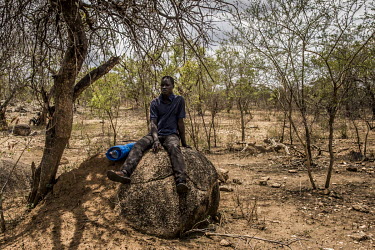 A South Sudanese refugee sits on a rock located in the plot of land allocated to him within the Bidibidi settlement area. South Sudanese refugees are given plots of land lent by Ugandan peasants. Upon...