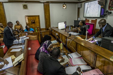 Dr Stella Nyanzi listens from the dock at the Buganda Road Chief Magistrate's court on 9 May 2019. One of her lawyers, Derrick Bazekuketta, talks with the magistrate during the cross examination of de...