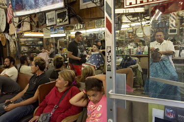Jesse Von Borstel and others cut hair as people wait at Jesse's Barber Shop on East Cesar E Chavez Avenue in Boyle Heights. Jesse has been working at this shop for forty years. Now he owns it. It's a...