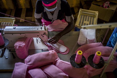 A worker stitches material together in a factory making sanitary pads.