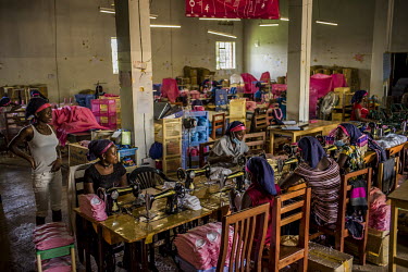 Staff using handpowered sewing machines in a factory making sanitary pads.