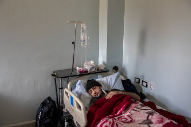An SDF fighter who had been injured in a mine explosion in Raqqa sleeps in his bed at a military hospital.