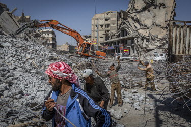 Men collecting scrap metal from the rubble of a destroyed building on the edge of Paradise Square, made infamous by ISIS who announced their caliphate with a parade of military hardware around the squ...