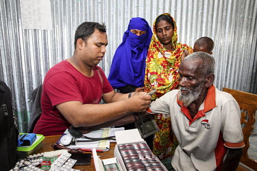 A medical worker takes an elderly patient's blood pressure at a small satellite clinic.