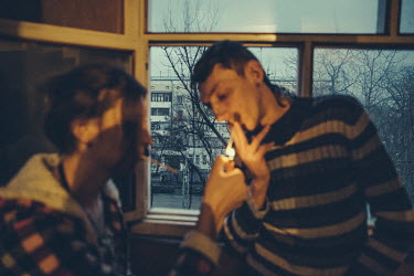 Ilona (20, left), lights a cigarette to Dmitry (34) at a secretly located shelter for the members of the LGBT community. Dmitry spent two months in this shelter after he was beaten and raped by the po...