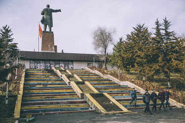 School children walking beside a Lenin monument.