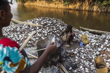 Women cooking clams on the banks of one of the many water channels that run among the mangroves. Women dive as deep as four metres to collect the clamps that they sell on skewers in nearby cities. Ent...