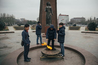 Youths gathered by an eternal flame monument.