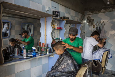 Mohammed Haj Ali cuts a young customer's hair during the busy run up to the Muslim holiday of Eid. Ali recalled how he had been detained and beaten by ISIS for smoking a cigarette.