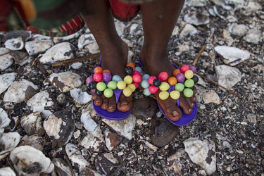 A woman's colourful footwear as she makes skewers of clams to sell in nearby cities. Women collect the clams from the beds of the many water channels that run among the mangrove forest, diving as deep...