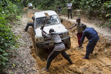 A team of bank agents, with help from accompanying policeman and drivers, dig one of their vehicles out of the mud on a road as they travel the remote region in order to pay state employees and civil...