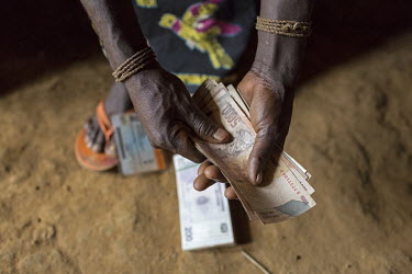 Congo, a teacher counting her salary after collecting it from a travelling bank agent.